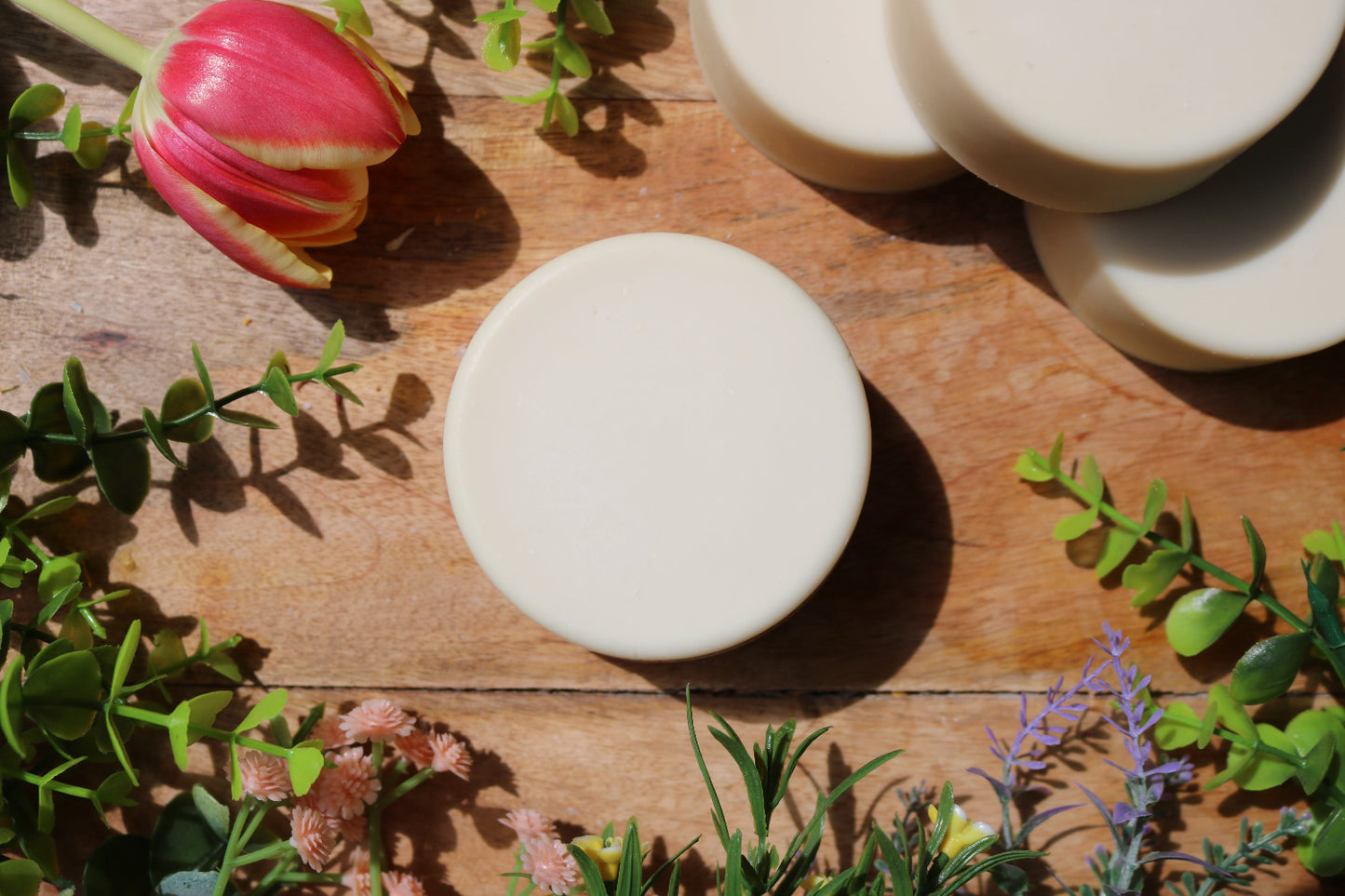 artisan soap bars on a wooden surface with greenery and flowers