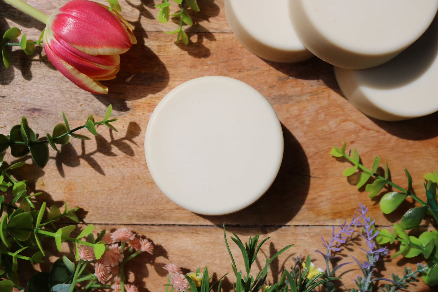 artisan soap bars on a wooden surface with greenery and flowers